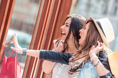 İki güzel moda model dışında gülüyor, eğleniyor iki genç kadın alışveriş torbaları ile poz.