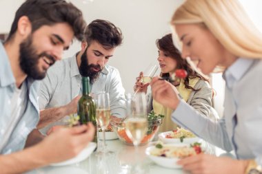 Evde birlikte yemeğe arkadaşları gülümseyerek. İnsanlar, yiyecek ve içecek, eğlence ve tatil kavramı.