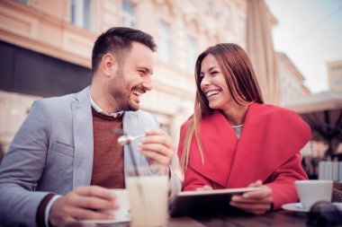 Genç çift birlikte bir şehir kafede otururken eğleniyor.