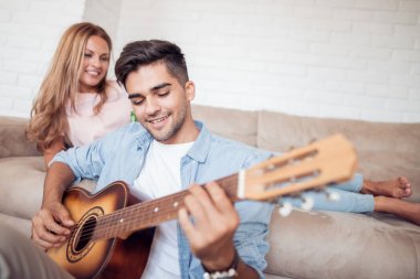 Yakışıklı adam gitar evde oturma odası ve içki bira ile kız arkadaşı serenat.