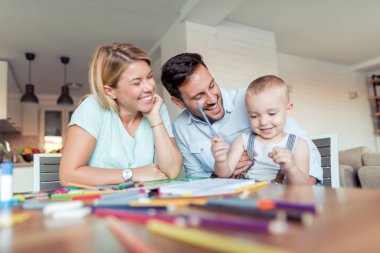 Anne ve baba oğlu çizmek için öğretmek.