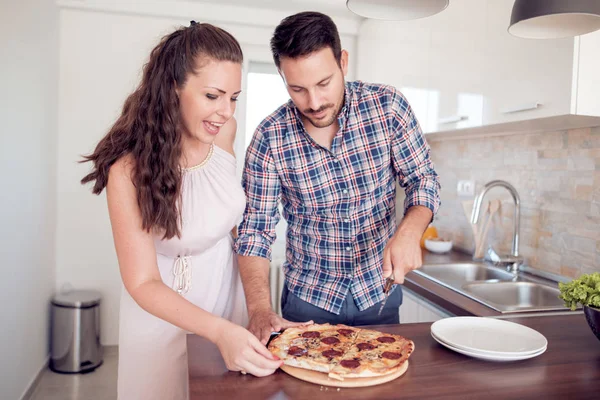 Happy couple eating pizza.Smiling family in the kitchen preparing and tasting food.