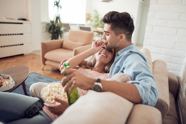 若いカップルは 彼らのアパートでリラックス ソファに横になっている 映画を見て ポップコーンを食べて — ストック写真