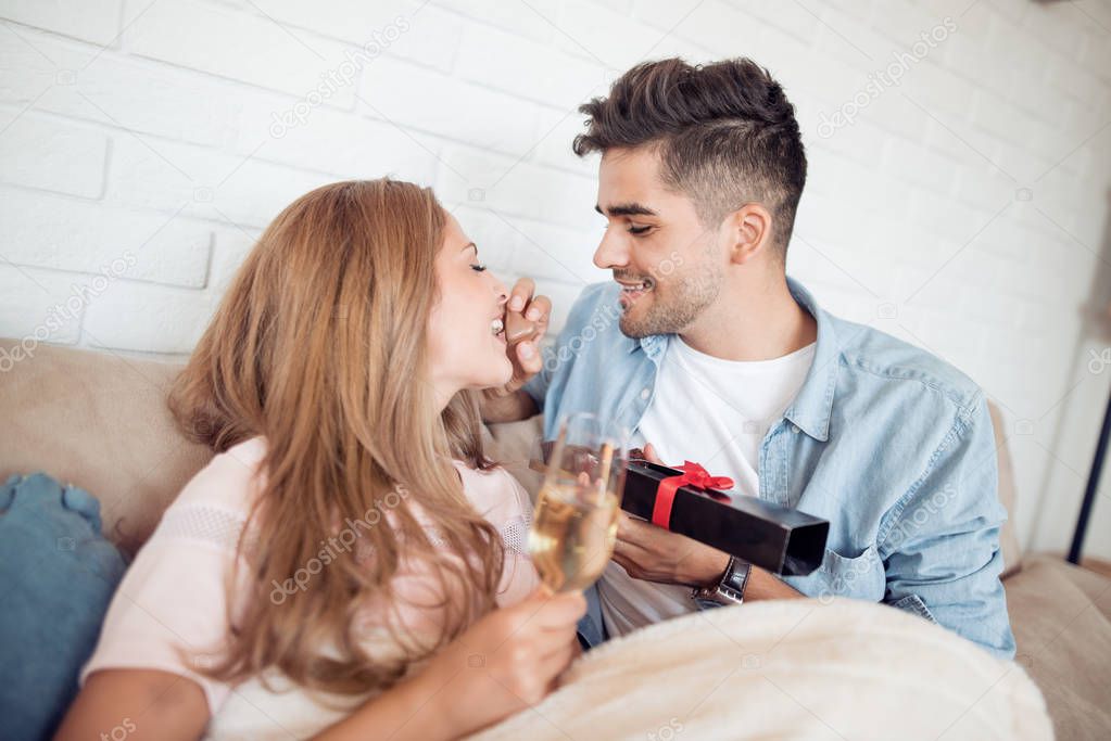 Portrait of young couple eating a heart chocolate cookie.Valentines couple sharing cookie,holds a glass of wine in hands.