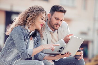 Bir dizüstü bilgisayar açık havada kullanarak ve mutlu görünüyordu genç Çift.