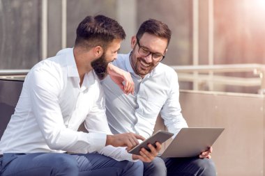 Dizüstü ve tablet tutarak ve birlikte çalışan iki iş adamları iş arkadaşları.