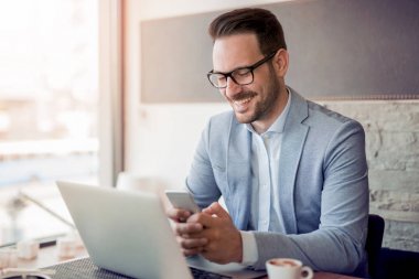 İşyerinde dizüstü bilgisayar kullanan genç beyaz işadamı portresi.