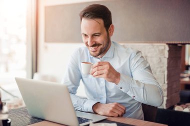 İşyerinde dizüstü bilgisayar kullanan genç beyaz işadamı portresi.