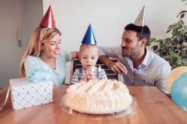 Mutlu aile evde oturma odasında birlikte bir doğum günü kutluyor.