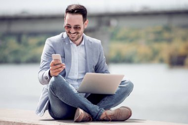 Dışarıda, telefon kullanarak ve bacaklar ile otururken bakıyordu çekici bir adam geçti.