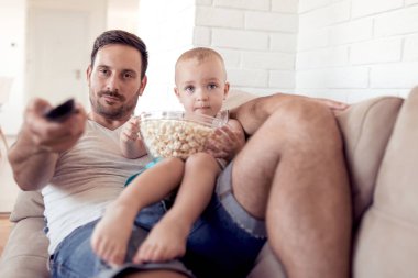 Baba ve oğul patlamış mısır yemek ve birlikte tv izlerken gülmekten.