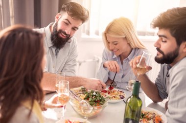 Bir grup mutlu genç arkadaş evde yiyip eğleniyor. Boş zaman, yemek, eğlence ve insanlar konsepti..