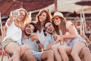 Arkadaş grubu yaz zevk. Gençlerin grup birlikte plaj ve al selfie üzerinde otururken eğleniyor mutlu.