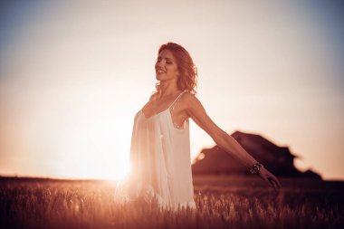 Buğday alan gün batımında güzel bayan. İnsan, doğa ve mutluluk kavramı.