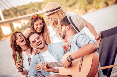 Birlikte şarkı ve sahilde gitar çalmak zevk arkadaş. Onlar tüm mutlu, eğleniyor, gülümseyen ve gitar çalmak vardır.