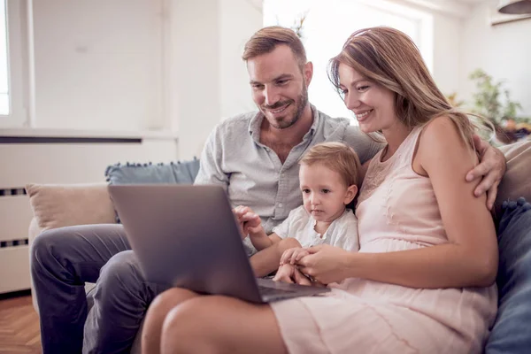 Evde Koltukta Oturan Bir Dizüstü Bilgisayar Kullanarak Neşeli Bir Aile — Stok fotoğraf