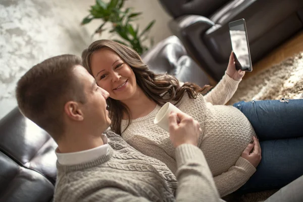 Χαρούμενο Ζευγάρι Χρησιμοποιώντας Tablet Στο Σπίτι Νεαρή Γυναίκα Είναι Έγκυος — Φωτογραφία Αρχείου
