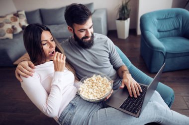 Film izlerken oturma odasında ve, dizüstü bilgisayar kullanarak genç Çift.