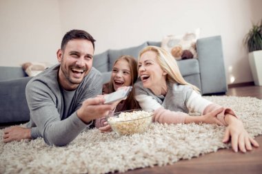 Baba, mather ve yerde yatarken, Tv izlerken ve patlamış mısır yemek kız.