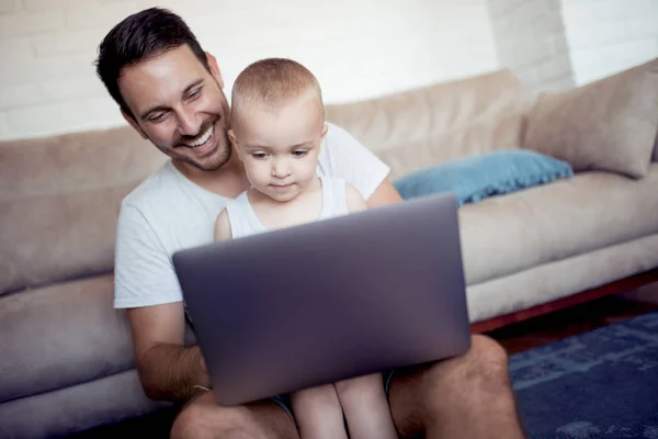 Family,fatherhood,technology and people concept-happy father and little son with laptop watch cartoon.