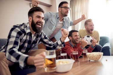 Mutlu arkadaşlar televizyonda futbol izleyip zaferi kutluyorlar. Dostluk, spor ve eğlence konsepti..