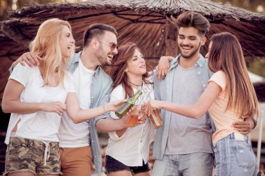 Soğuk bir bira ile sahilde eğleniyor arkadaş grubu.