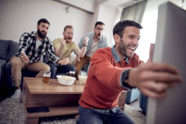 Grup arkadaşları-futbol izlerken futbol oyun televizyon ve kutlama hedefte fanlar.