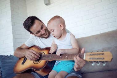 Gitar çalmaya ve oğlu üzerinde kanepede otururken arıyor Peder. Baba oğlu nasıl gitar öğretim.