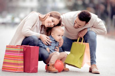 Satılık, tüketim ve aile kavramı - küçük çocuk ve şehirde alışveriş torbaları ile mutlu aile.