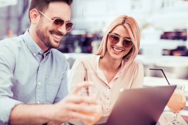 Mutlu çift birlikte kahve dükkanında vakit, dizüstü bilgisayar kullanarak. Office kavramı dışında geçici toplantının. 