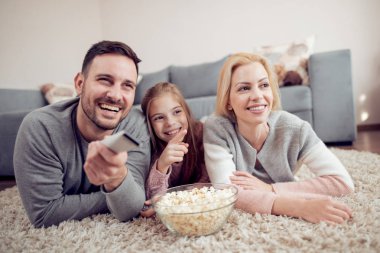 Baba, mather ve yerde yatarken, Tv izlerken ve patlamış mısır yemek kız.