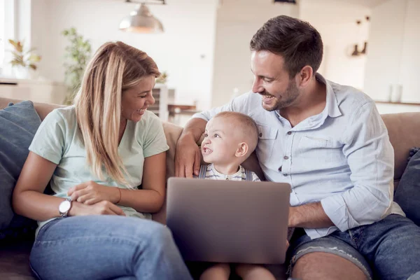 Happy family using laptop together on sofa — Stock Photo, Image