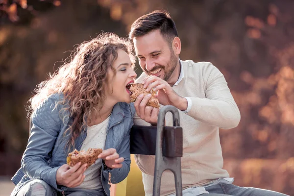 Couple eating sandwich and talking  in city park. — Stock Photo, Image