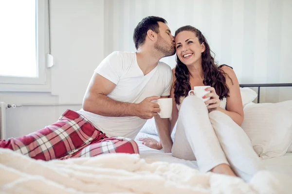 躺在床上喝咖啡对年轻夫妇的图片 — 图库照片