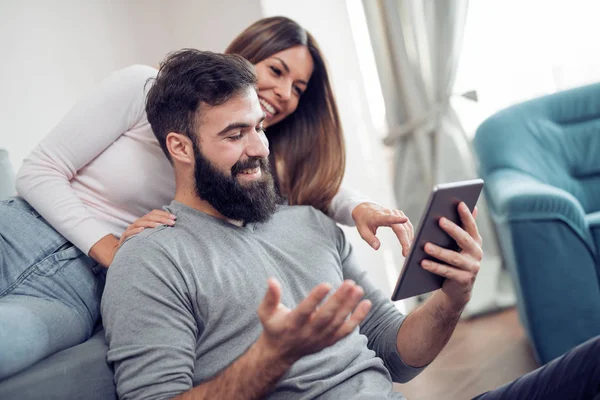 Ζευγάρι χρησιμοποιώντας ένα tablet στο σαλόνι — Φωτογραφία Αρχείου