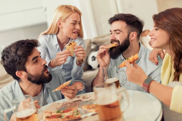 Amigos assistindo TV em casa enquanto comem pizza — Fotografia de Stock