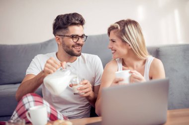 Kahvaltı yaparken bir dizüstü bilgisayar kullanarak çift 