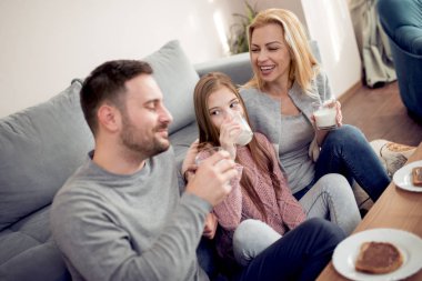 Üç sabahları kahvaltı ev onların oturma odasında birlikte olan aile gülümseyen .