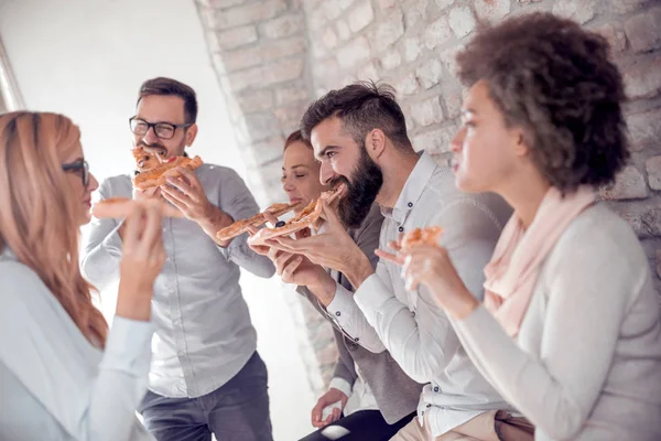 Business,food, lunch and people concept-happy business team eating pizza in office.