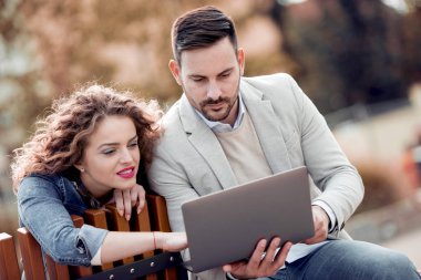 Açık havada eğleniyor ve gülümseyerek, tablet üzerinde seyir mutlu genç Çift.