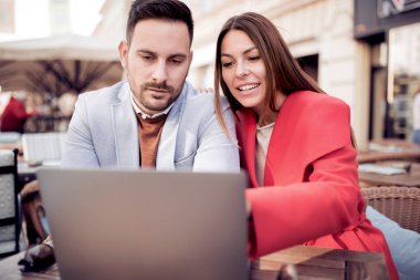 Genç çift kafede otururken dizüstü bilgisayar kullanarak