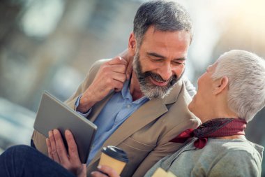 Olgun çift açık havada tablet ile gülümseyen mutlu. İnsanlar, sevgi, teknoloji ve yaşam tarzı kavramı.