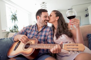 Oturma odasında, dinleme ve erkek öpüşme kadın gitar çalmak adam