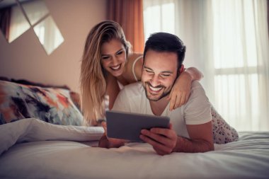 Genç çift yatakta tablet ile vakit