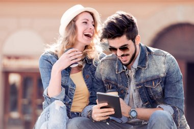 Genç kahve fincanı ile çift ve Şehir Parkı içinde oturan elinde tablet