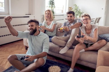 Modern apartmanda oturuyor ve video oyunları oynarken arkadaş grubu