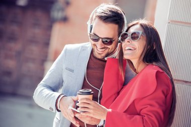 Mutlu çift kulaklık smartphone sokakta müzik paylaşımı ile