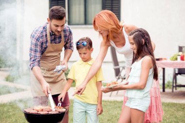 Mutlu genç aile öğle yemeği Barbekü bahçede güneşli günde partisi.