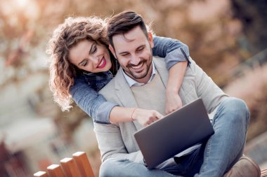 Açık havada eğleniyor ve gülümseyerek, tablet üzerinde seyir mutlu genç Çift.