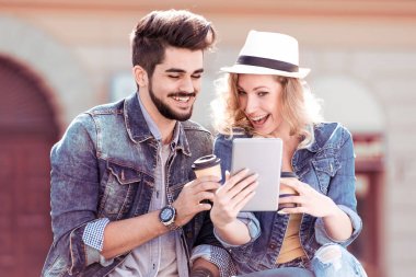 Genç kahve fincanı ile çift ve Şehir Parkı içinde oturan elinde tablet